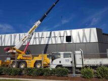 Site maintenance at Tuggerah Super Centre. A crane is about to lift concrete panels from the side of a building